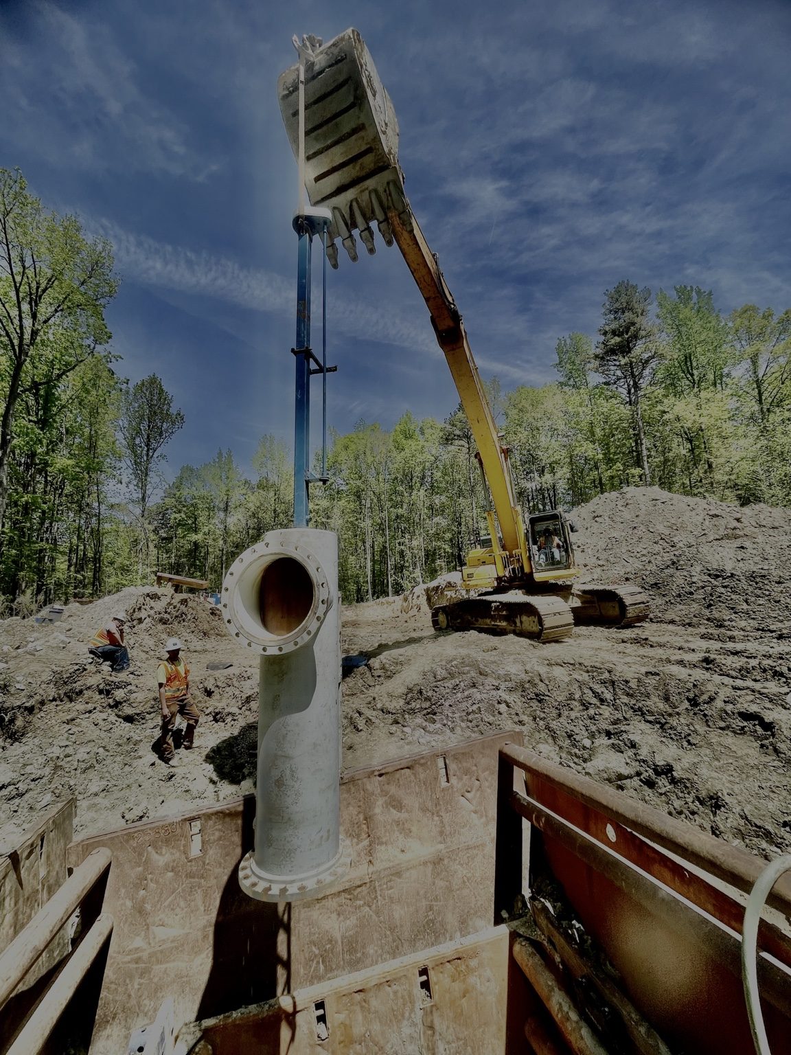 Large fabricated fitting being lowered into an excavation