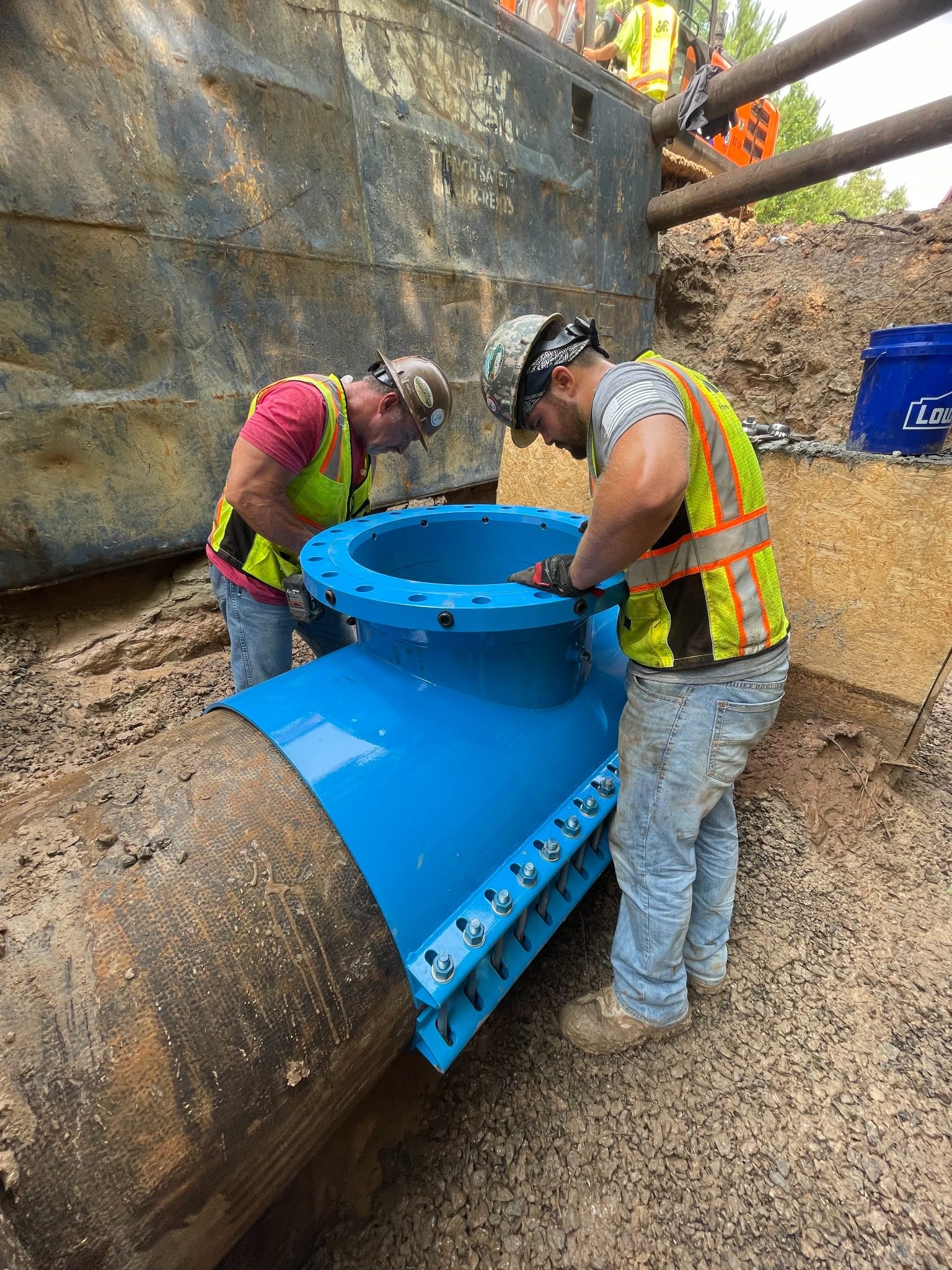Crew installing a blue line stop sleeve on a large water main